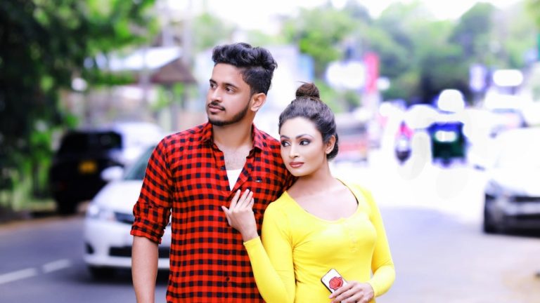 A young couple standing on a street looking away.