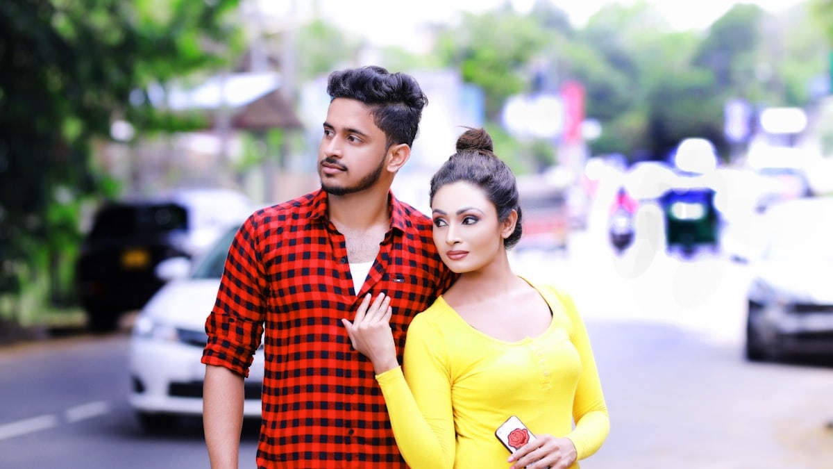 A young couple standing on a street looking away.